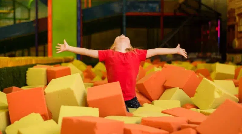 Enfant épanoui dans un bac à mousse d'un parc de jeux couvert réalisé par Play In Business.