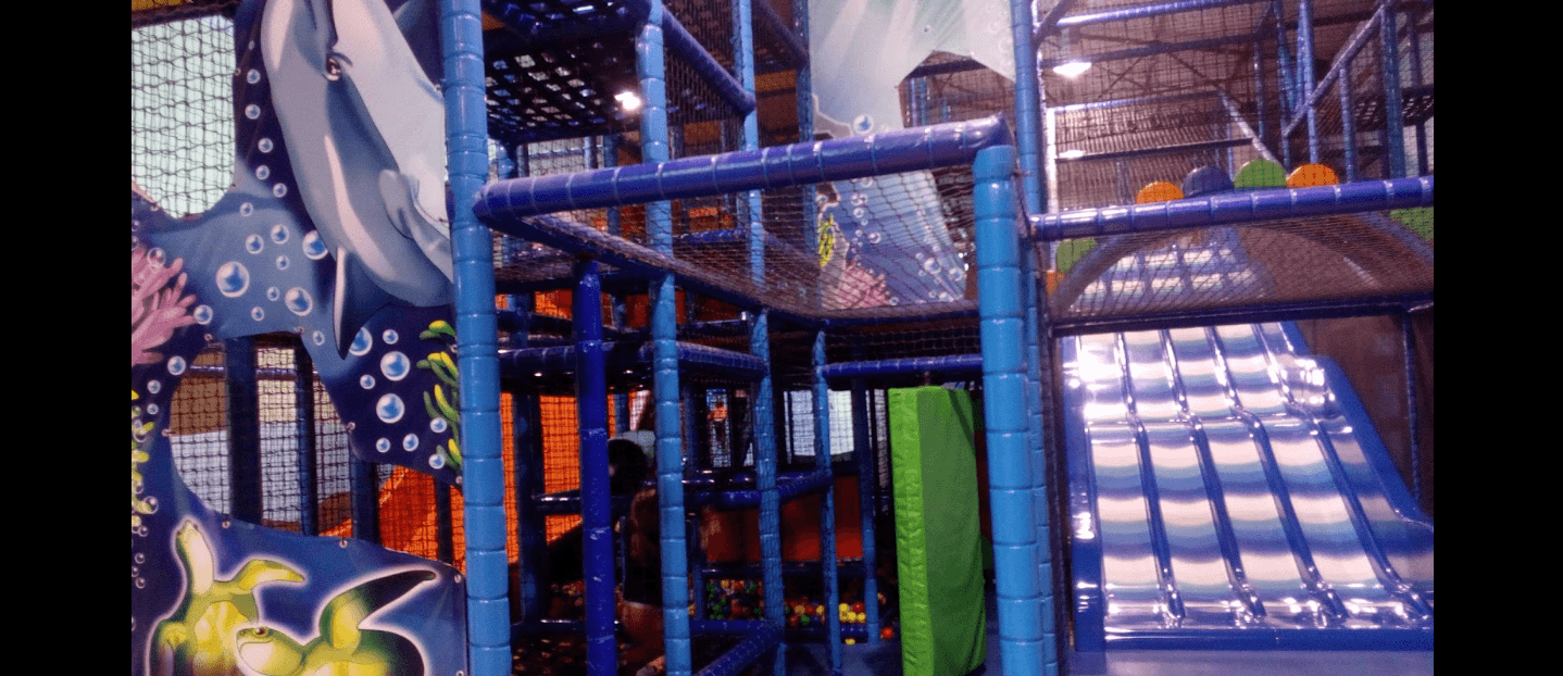 Structure de jeux indoor tubulaire sur le thème marin avec toboggan à vagues et décors aquatiques, réalisée sur mesure par Play In Business pour le parc L'île aux délires à Sorbiers.