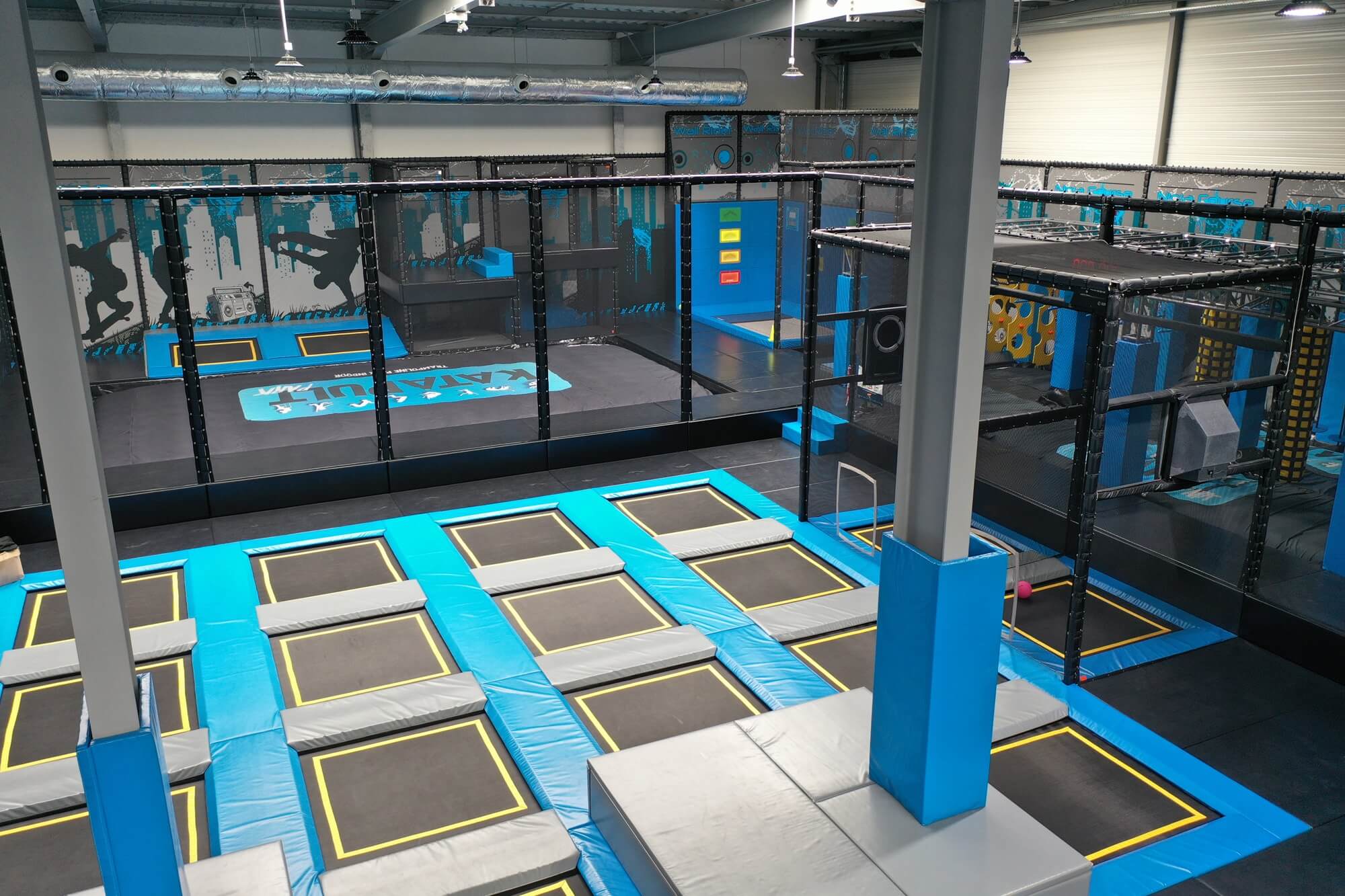 Vue d'ensemble du Trampoline Park Katapult à Albertville, aménagé sur mesure par Play In Business, comprenant une grande zone de saut principale et un parcours Ninja avec thématique urbaine.